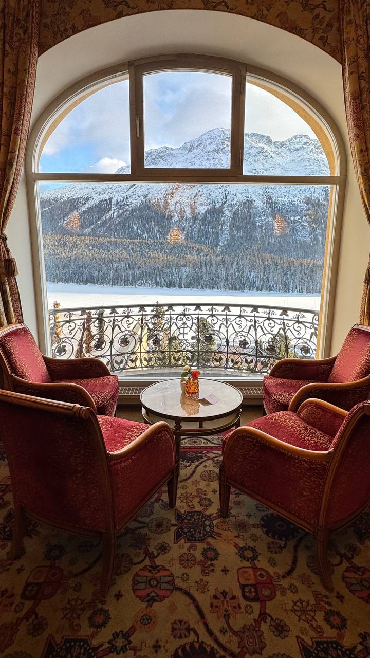 Frozen alpine lake framed by an arched hotel window — luxury travel consultant for Courchevel and the Alps