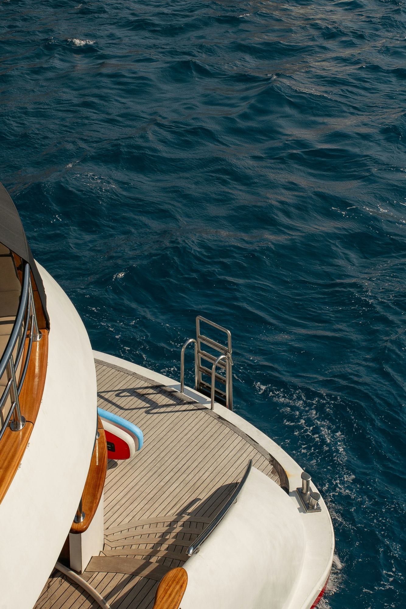 Yacht stern with teak deck above deep blue sea — private yacht charter planning and on-the-ground concierge